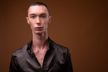 Obraz premium Young handsome androgynous businessman against brown background