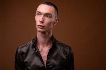 Obraz premium Young handsome androgynous businessman against brown background