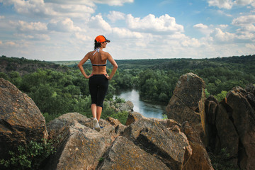 young girl watching the beautiful view from the top of a cliff