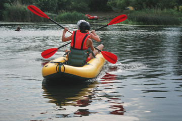 Back view. Two  man  enjoy water rafting activity at river. Rafting family on holidays