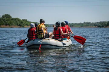 Group of men and women, enjoy water rafting activity at river. Rafting family on holidays