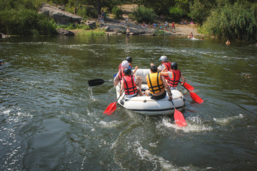 Group of men and women, enjoy water rafting activity at river. Rafting family on holidays