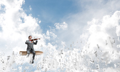 Handsome violinist play his melody and symbols fly around in air
