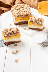 Piece of pumpkin homemade cake with white cream on a white background. Festive dessert concept.