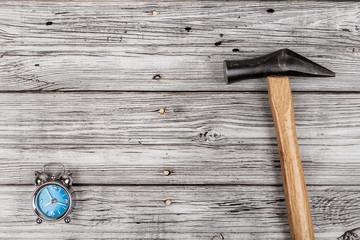 Alarm clock and a hammer on wooden background