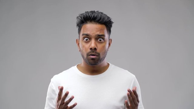 emotion, expression and people concept - shocked indian man over grey background