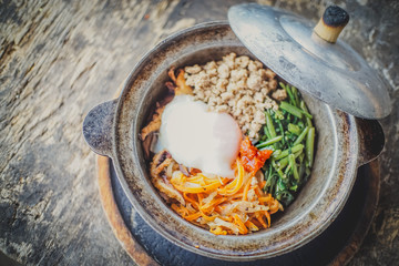Top view Homemade Bibimbap rice in pot,on old wood table background.