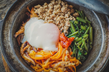 Close-up of Homemade Bibimbap rice in pot,on old wood table background.