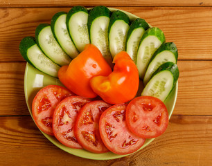 Cucumbers, tomatoes and peppers cut into pieces on a plate.