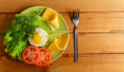 Fried eggs, pieces of vegetables, bread and fork on the table.