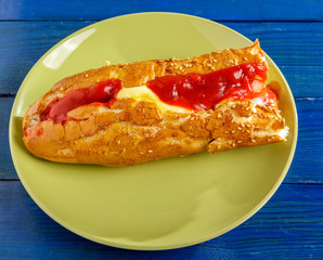 Sandwich with sausage and sauces on a plate on a blue background.