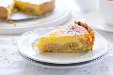 Delicious banana cake (cheesecake) with tea cup on white table. Teatime concept. Copy space