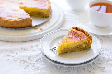 Delicious banana cake (cheesecake) with tea cup on white table. Teatime concept. Copy space