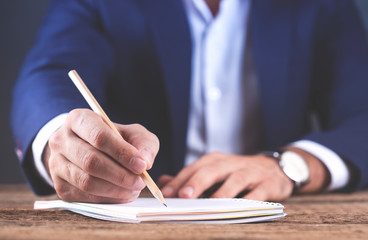 man hand pencil with notepad on wooden desk