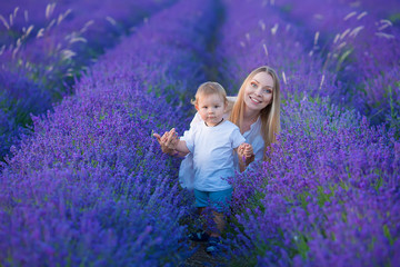 Happy mom with cute son on lavender background. Beautiful woman and boy in meadow field. Lavender landscape with lady and kid enjoying aroma and vivid colors. Family picture in colorful lavender view