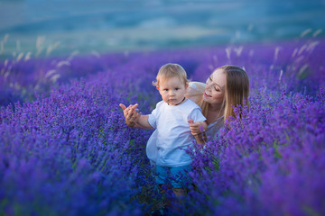 Happy mom with cute son on lavender background. Beautiful woman and boy in meadow field. Lavender landscape with lady and kid enjoying aroma and vivid colors. Family picture in colorful lavender view