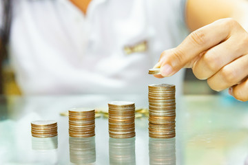 Saving money, save money concept, woman hold stacking coins into increasing columns.