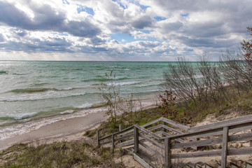 Stairs To The Beach. Wooden staircase leads to a wide sandy beach on the shore of scenic Lake Michigan on a beautiful and windy summer day. 
