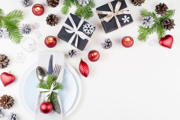 Christmas table setting with plates, silverware, presents, candles and decorations, copy space