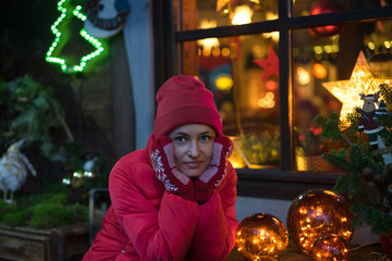 Portrait of beautiful young smiling woman in red hat with defocused Christmas lights in the background