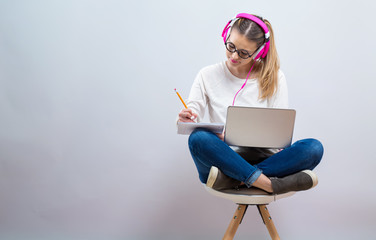 Young woman studying on her laptop computer on a gray background