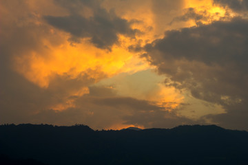 Fototapeta na wymiar dark sunset sky with bright orange clouds against the black silhouettes of the mountains. mountain sunset. mountain dawn