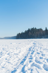 Winter landscape of a frozen lake with a trail for walking