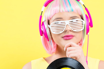 Woman in a colorful wig holding a vinyl record on a purple background