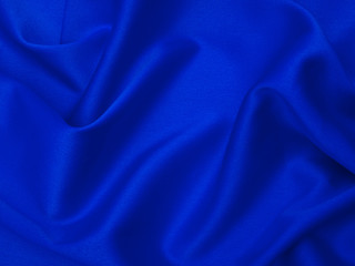Blue fabric is laid out waves. Blue silk fabric for background or texture.