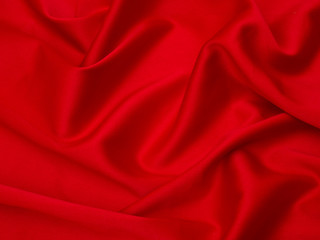 Red fabric is laid out waves. Red silk fabric for background or texture.