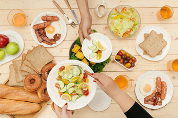 Enjoying dinner with friends.  Top view of group of people having dinner together while sitting at wooden table