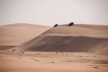 Fototapeta na wymiar two cars on crest of sand dune