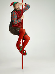 The happy smiling friendly man dressed like a funny gnome or elf posing on an isolated gray studio...
