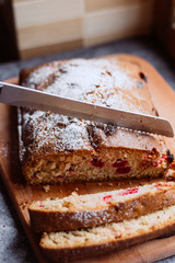 Homemade traditional sweet  cherry pie sprinkled with sugar powder. A woman cuts a pie
