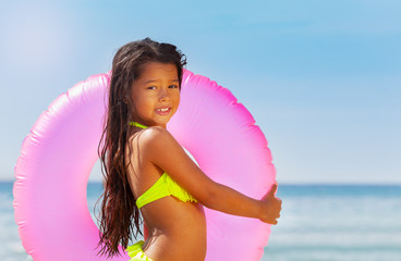 Little Asian girl with swimming ring on the beach