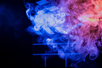 Black and white clapperboard for cinema close up among multicolored red and blue smoke in a man’s hand giving a command to start shooting on a black isolated background