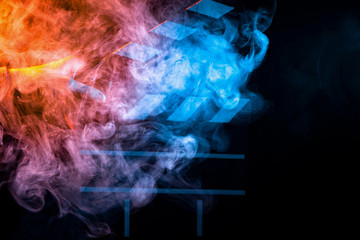 Black and white clapperboard for cinema close up among multicolored orange and blue smoke in a man’s hand giving a command to start shooting on a black isolated background