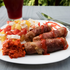 Chevapchichi. Meat sausages with vegetable salad, ketchup and adjika on white plate. Dish of Balkan cuisine.