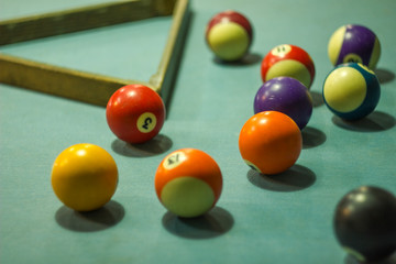 Blurred multicolored billiard balls on a blue table cloth with shadows and a triangle. numbers on billiard balls.