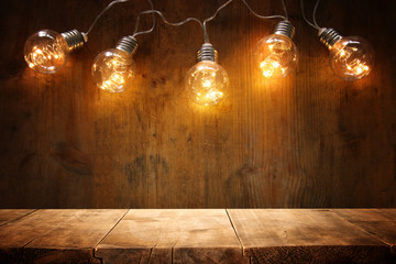 empty table in front of Christmas warm gold garland lights on wooden background