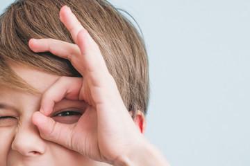 Jolly boy shows shackle of his glasses with his fingers