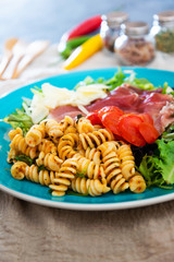 Salad with fusilli pasta accompanied tomatoes, mozzarella, smoked ham and italian cheese