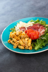 Salad with fusilli pasta accompanied tomatoes, mozzarella, smoked ham and italian cheese