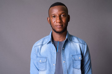 Young handsome African man with short hair against gray backgrou