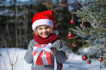 Cute little boy with christmas gift im winter forest