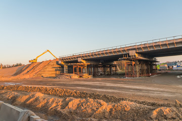 the construction of the road, an excavator on a mountain of sand