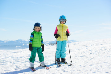 Smiling children skiing in the mountains during winter holiday