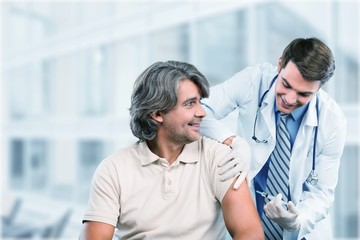 Handsome doctor making vaccination to male patient on background