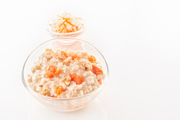 Fototapeta na wymiar Oatmeal with pumpkin and nuts in a glass plate on a white background. Close-up. Copy space