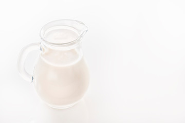 Glass jug with milk on a white background. Close-up. Copy space